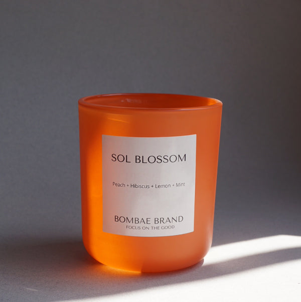 Hand-poured with 100% natural soy wax, our Sol Blossom candle fills your space with hibiscus, peach, lemon & mint. Clean burning, cruelty-free & made for sunlit moments. Shop Bombae Brand.

